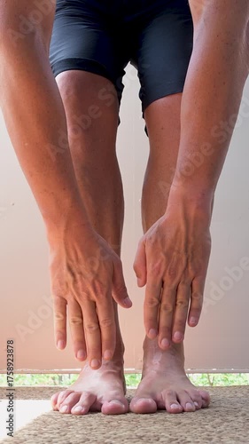 Fit man stretching hamstrings and touching his toes.Vertical video