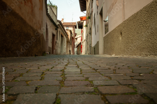 Bild auf Leinwand Low angle view of narrow old cobblestone street between aged buildings