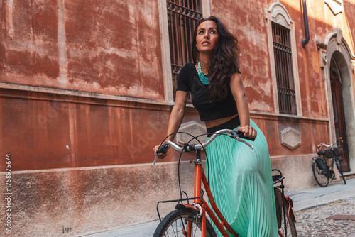 Woman travelling on bicycle, enjoying summer vacation in an old italian city