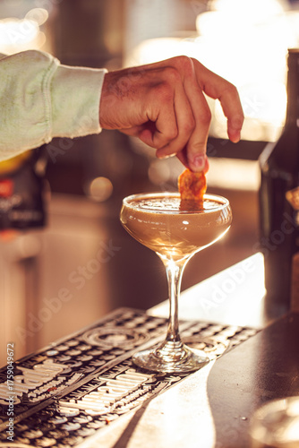 A bartender adding the finishing touches to an espresso martini at a sunny food restaurant bar 