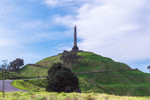 Peaceful park landscape with a trail, leading up to a tall monument on the hilltop