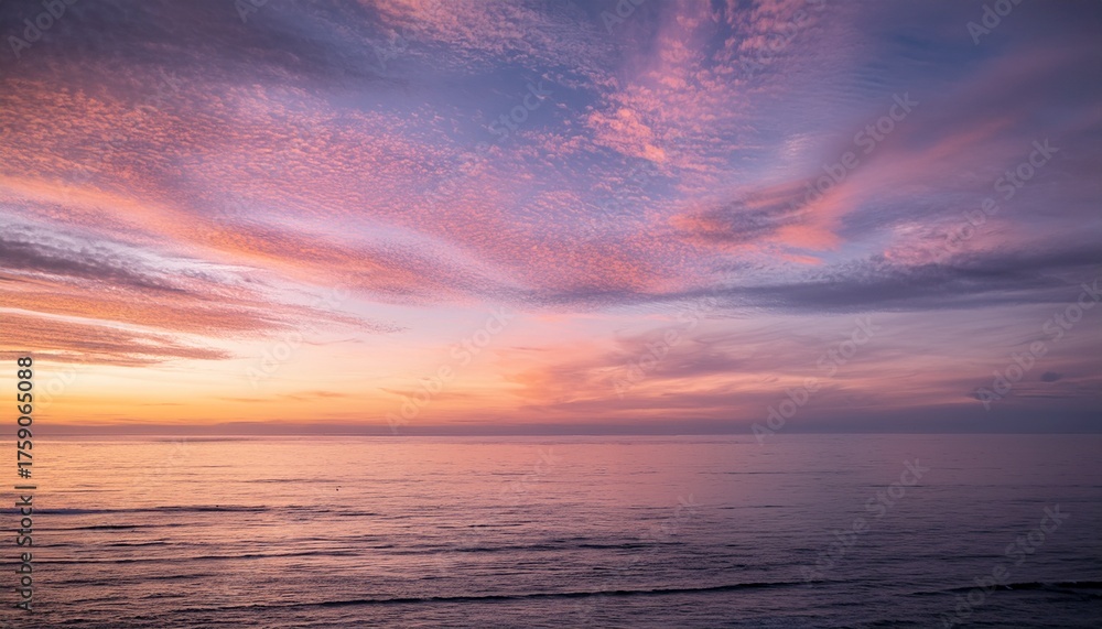 Obraz premium Evening sky with pink cirrus clouds over calm ocean water at sunset 