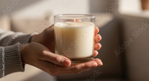 Woman holding burning candle in glass for home ambiance or decoration