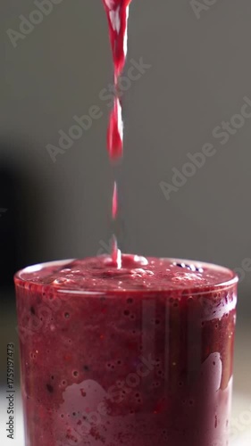 Pouring a healthy berry smoothie into a glass with blueberries