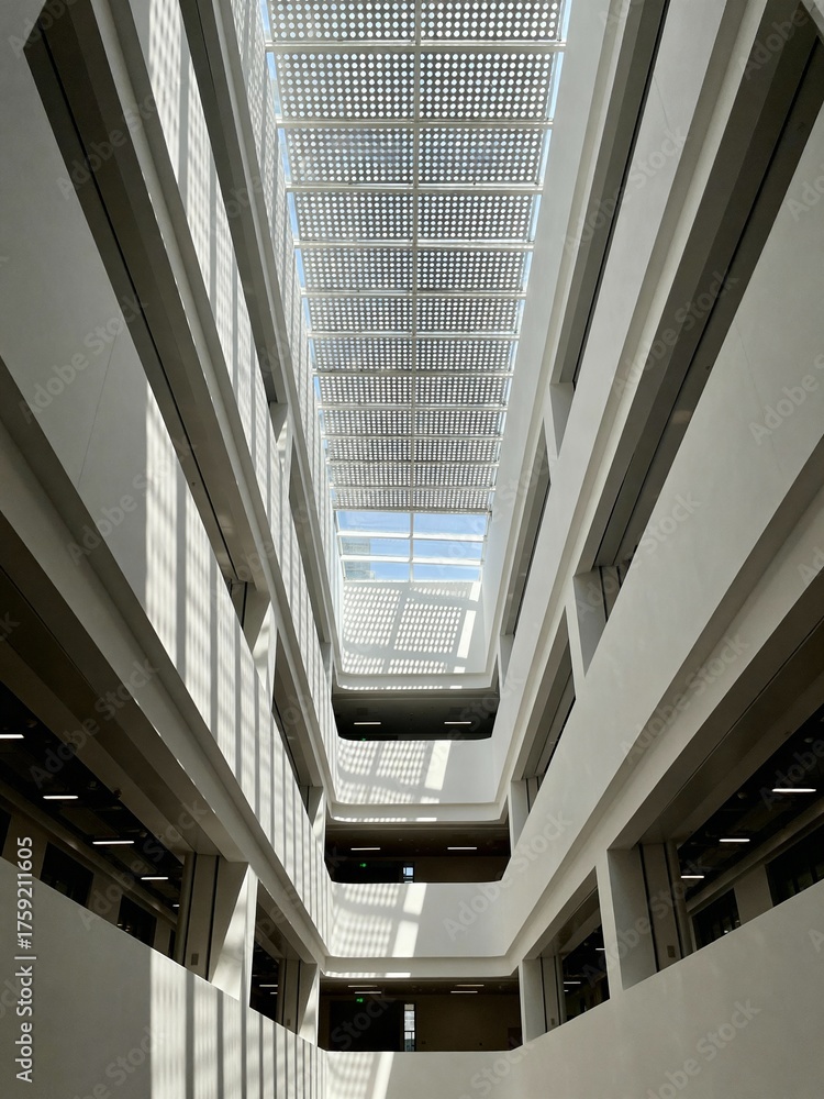 Obraz premium Modern building interior with atrium and skylight, looking up at geometric patterns and natural light