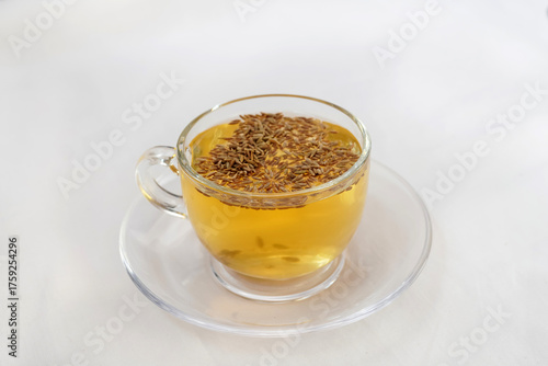 Black cumin seeds,shah jerra,Nigella sativa and its extracted water in a transparent glass on brown wooden surface. Selective focus.