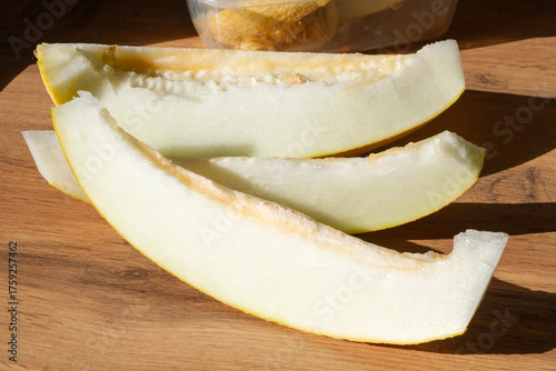 slices of sliced melon are placed on a wooden surface in sunlight