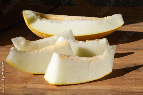 slices of sliced melon are placed on a wooden surface in sunlight