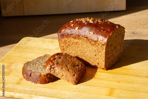 sliced rye bread with bran and seeds next to 2 slices of bread on a wooden surface, side view