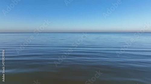 Calm expanse of water under a gradient sky. Gentle ripples on the water. Horizon line separates the sky and water
