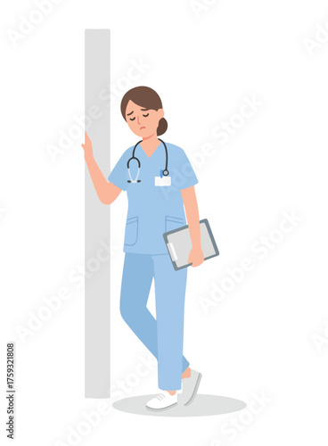Exhausted female nurse in blue scrubs feeling sad and tired from overwork, leaning against a wall with a clipboard.
