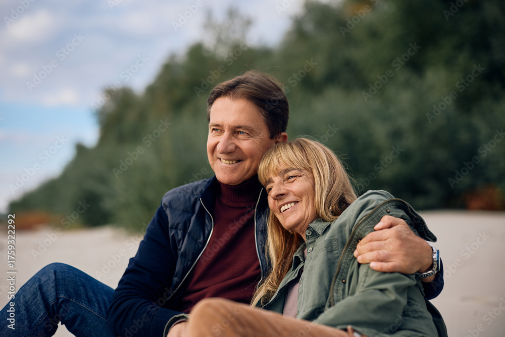 Fototapeta premium Happy mature couple sitting embraced in nature in autumn.