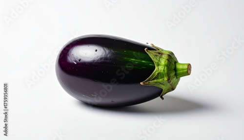 “Single horizontal eggplant with glossy dark purple skin and green calyx on white surface and background”