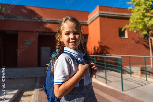 Pretty little girl standing in school uniform