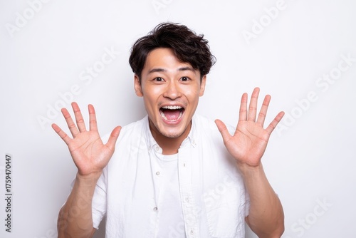 Thrilling Wow Experience: Excited Young Asian Male Expressing Happiness with an Enthusiastic Gesture Against a Bright White Background