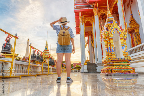 Female tourist in hat with backpack at a Buddhist temple