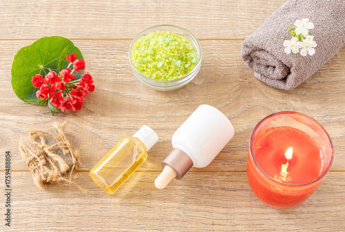 Towel with body care products and verbena flowers on the wooden background.