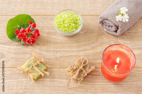 Towel with body care products and verbena flowers on the wooden background.