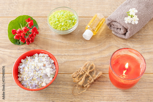Towel with body care products and verbena flowers on the wooden background.
