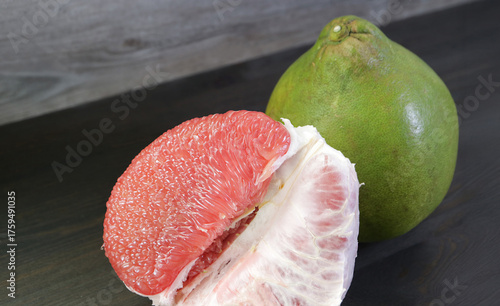Delectable Vibrant Red Pomelo Fruit with the Whole Fruit in the Backdrop