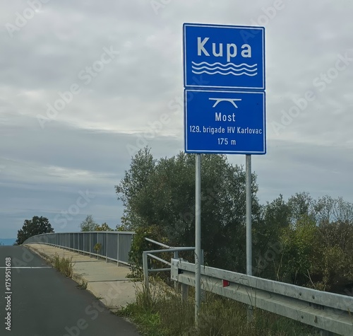 A board with the name of the river at the bridge over the Kupa River in Croatia.