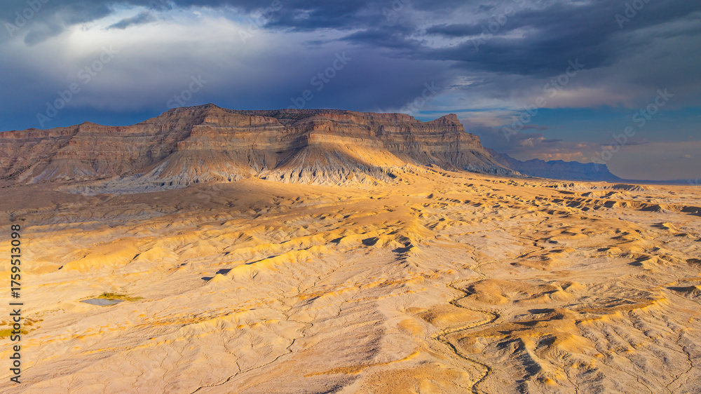 Fototapeta premium Aerial view of barren desert cliffs in Utah. Aerial drone image of rugged barren cliffs and layered mesa in Utah desert landscape.