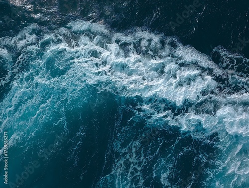 A dynamic ocean wave curls and crashes, showcasing the raw power and beauty of the sea with vibrant blue hues and frothy white foam.