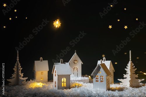A miniature Christmas village in a snowy night setting with pine trees and a glowing star.