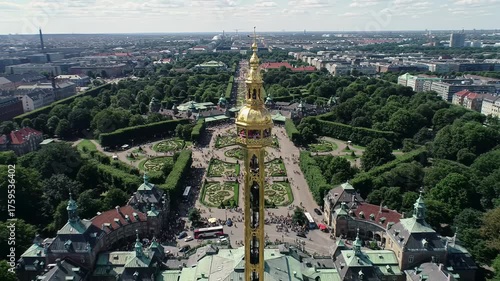 Breathtaking aerial drone video of vibrant Tivoli Gardens, Copenhagen, featuring the Golden Tower, happy people, and busy city streets. Grand urban landmark concept