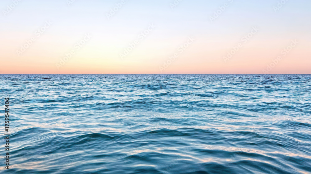 Fototapeta premium Calm blue ocean meets soft pink sky at sunset, creating dreamlike atmosphere