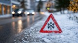 Triangular road sign with a snowflake symbol covered in snow, warning of icy and slippery roads, representing winter driving safety and hazardous weather conditions