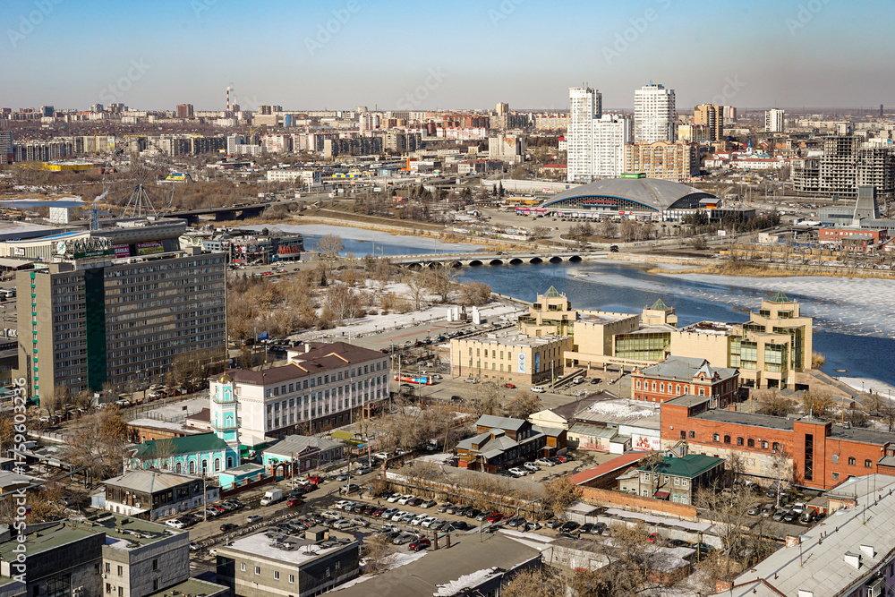 Fototapeta premium Panoramic view from above of the city of Chelyabinsk in Russia Many high-rise buildings of various types are visible, the sky is blue and clear, the weather is cold The Miass River is also visible.