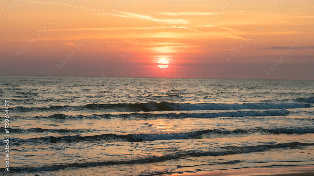 Obraz premium Vibrant sunset over the ocean, with warm hues of orange and red illuminating the water.