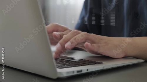 Person typing on laptop with data graph overlay, analyzing business data and technology analytics in modern digital workspace while working remotely using keyboard and hands