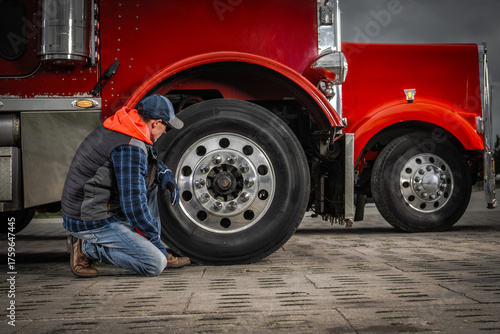Behang Truck Driver Inspects Tire at Service Location