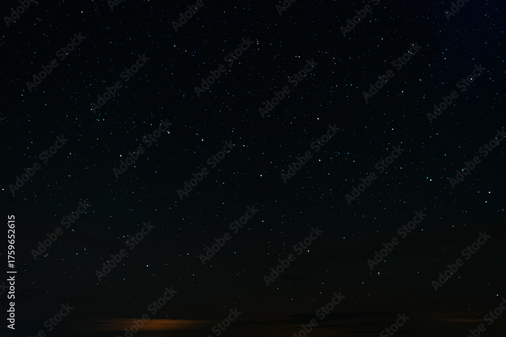 Fototapeta premium A long-exposure photo of the night sky showing streaks of stars forming short trails, creating a mesmerizing cosmic pattern in deep darkness.