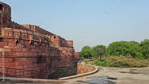 Historic red sandstone walls of Agra Fort with deep moat visible. Ancient Mughal fortress architecture in Agra, India.