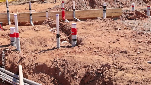Workers are laying out wastewater plumbing pipes in freshly dug construction site during work day