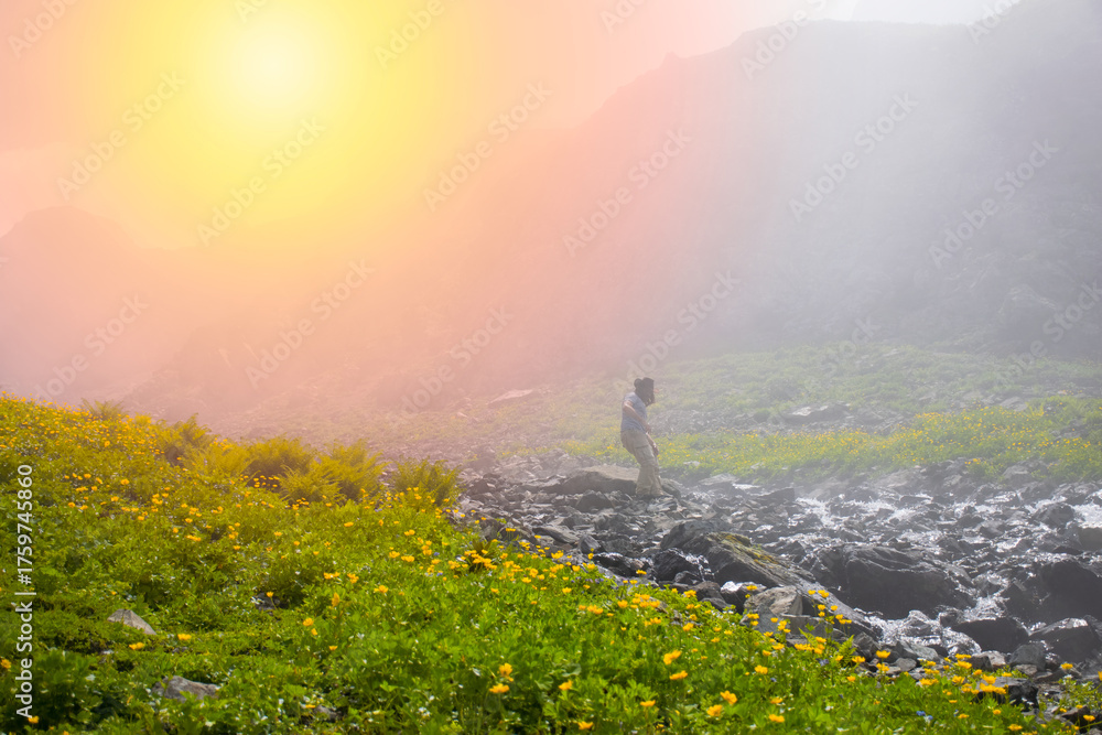 Fototapeta premium Man jumping over river on top of mountain in fog..