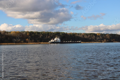 a ferry with cargo on the river, with a forest in the background,