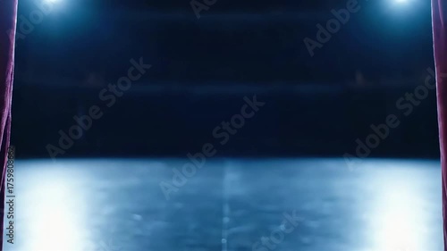 Luxurious red velvet stage curtains opening to reveal a dark empty theater stage illuminated by brilliant spotlights setting the mood for a live show