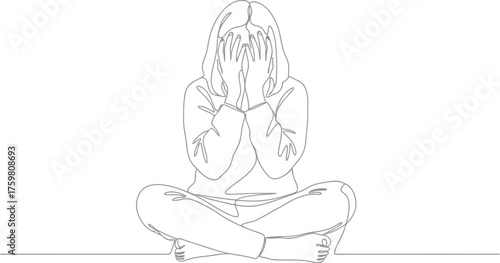 Woman sitting cross legged covering her face with hands
