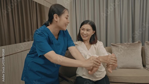asian female caregiver assisting senior woman with physical therapy exercise at home during rehabilitation process to improve mobility strength and overall health care support in daily life