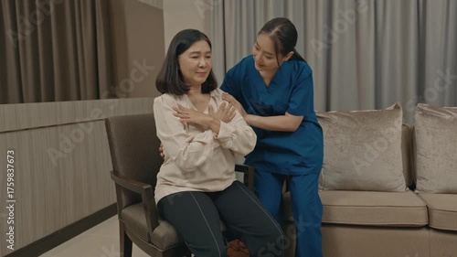 asian female caregiver assisting senior woman with physical therapy exercise at home during rehabilitation process to improve mobility strength and overall health care support in daily life