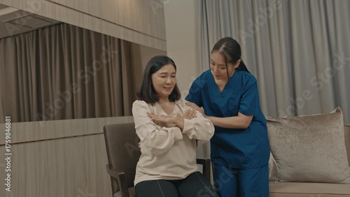 asian female caregiver assisting senior woman with physical therapy exercise at home during rehabilitation process to improve mobility strength and overall health care support in daily life