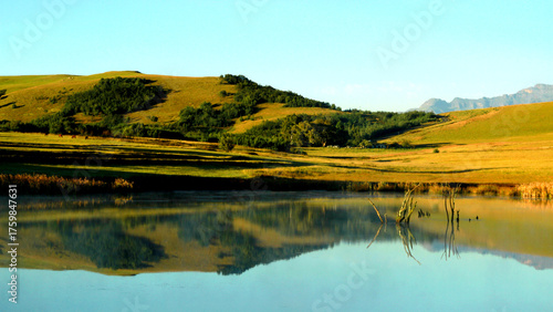 Beautiful landscape photo of a dam with a boat in the foreground, trees, mountains in the background, and reflecting in the dam. 