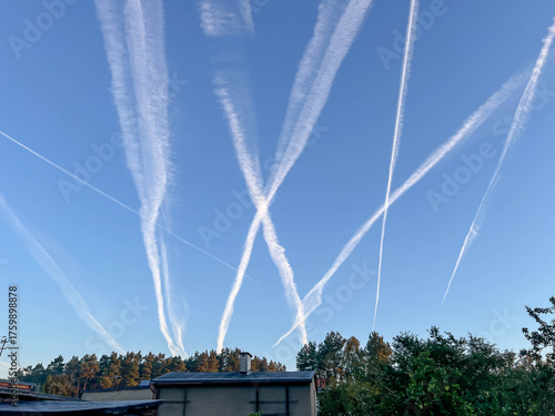 A blue sky with streams of condensation from passing airplanes