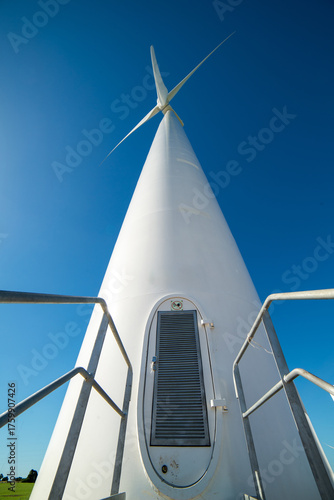 Towering wind turbine against blue sky in scenic renewable landscape