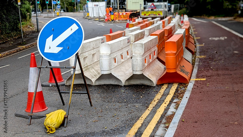Roadworks scene with a blue keep left arrow sign and orange/white temporary barriers, illustrating traffic management, construction, and urban infrastructure