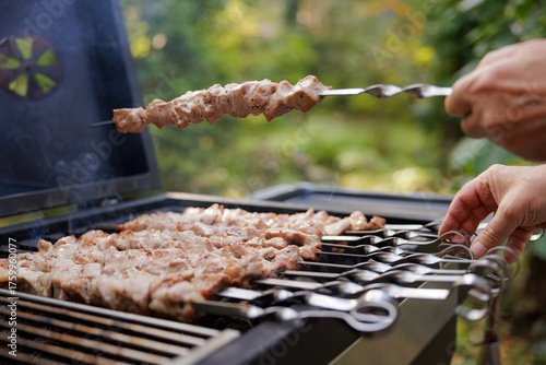 Tapeta Juicy meat skewers sizzle on the grill while friends enjoy a lively summer gathering outside under clear blue skies